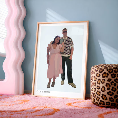 A framed custom People Portrait of a couple leaning against a blue-grey wall on a pink rug, next to a pink wavy mirror and a leopard print ottoman.
