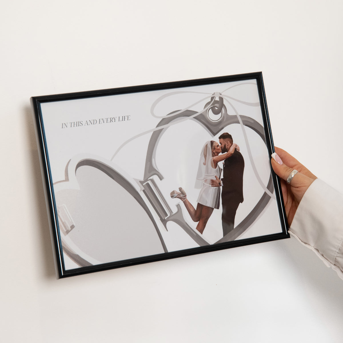 Framed Locket Portrait of a couple kissing being held against a white wall.