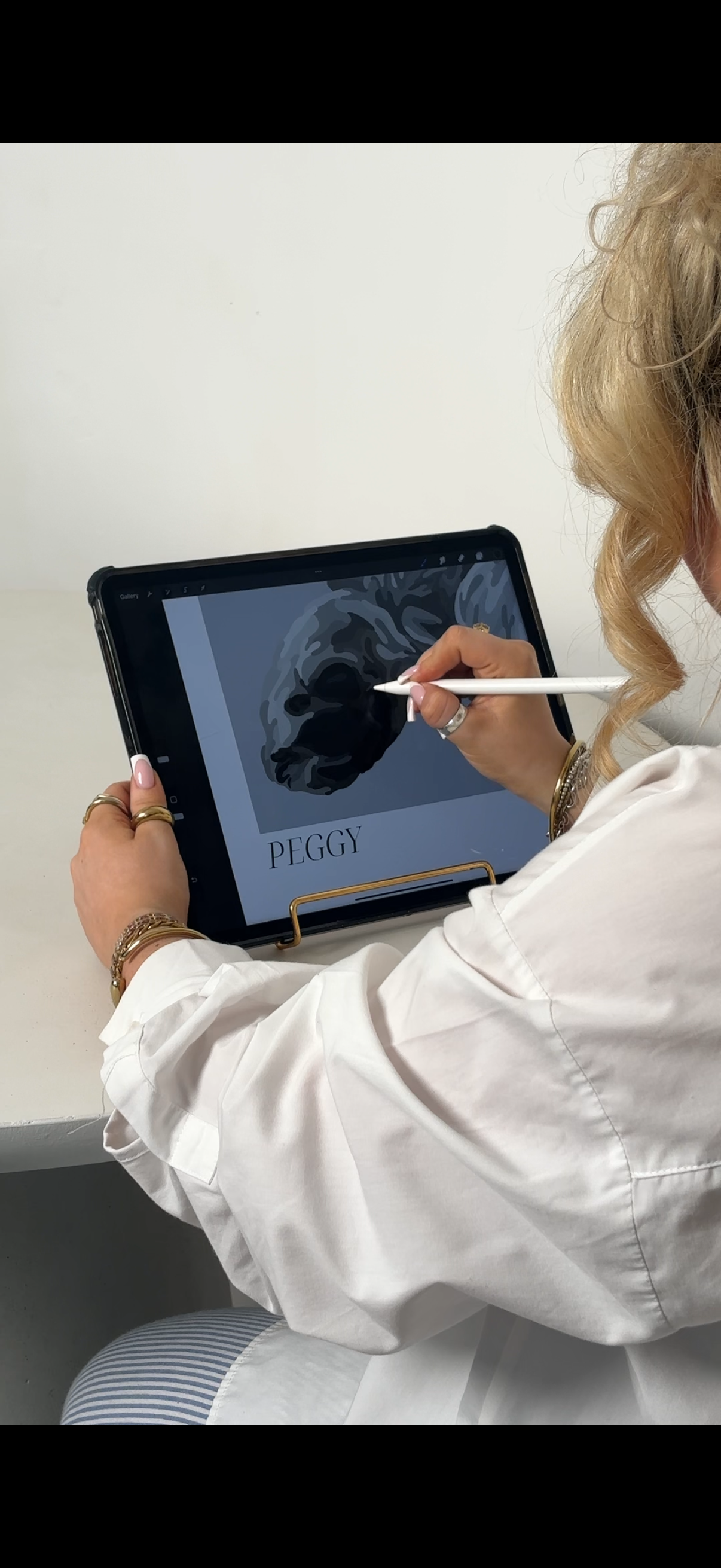 Photo of someone drawing on a tablet from behind.