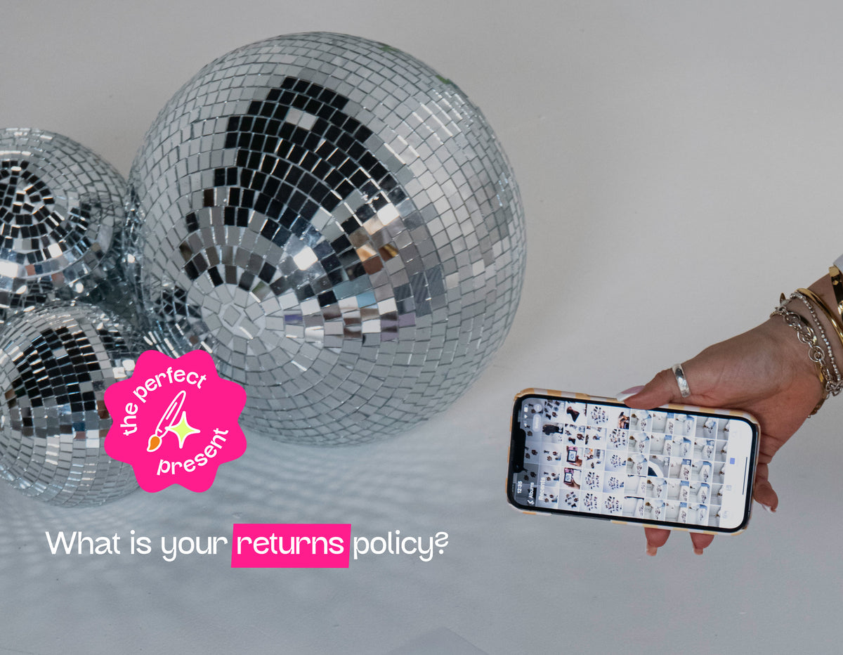 Three large silver disco balls on a white floor, with a hand holding a smartphone showing a snippet of a photo library and the text 'What is your returns policy?' on the right.